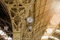 Round Roman clock and glass roof of railway or subway station. Twelve o`clock, seven past twelve pm, sunflare