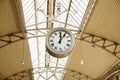 Round Roman clock at railway or subway station. Twelve o`clock, five past twelve pm, close-up