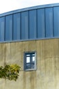 Round roof buildng with blue metal grate accent exterior and smooth cement walls with a tiny window in the shade Royalty Free Stock Photo