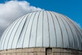 the round roof of the dome on the background of the sky and clouds. A round unusual building for storing grain crops or synthetic Royalty Free Stock Photo