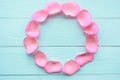 Round rose petals frame on blue wooden background, top view.