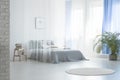 Round rug near bed under veil in blue and white bedroom interior