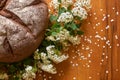 Round rye bread with molasses on the old scratched mahogany table. Fresh home baked bread and spiraea flowers