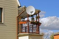 Round satellite dish on an open balcony with flowerpots and flowers on a private house Royalty Free Stock Photo