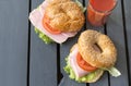 2 round sesame buns with ham, tomato, lettuce leaf, a glass of tomato juice, top view