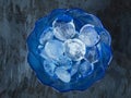 Round shaped ice cubes in a glass dark blue vase on a gray background for cooling drinks Royalty Free Stock Photo