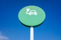 Round sign of electric car recharging station, with blue sky background and copy space Royalty Free Stock Photo