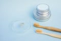 Round silver cans, put one on one, two bamboo toothbrushes and glass cup with paste smudge on light blue background. Eco freindly Royalty Free Stock Photo