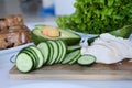 Chopped cucumbers, slices of chicken breast and avocado halves on a wooden cutting board with lettuce on the background Royalty Free Stock Photo