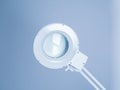 Round small white medical operating lamp in doctor`s office. Light blue interier back