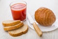 Round smoked sausage, knife in plate, tomato juice, bread Royalty Free Stock Photo