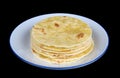 Round soft corn mini tortillas pancakes on plate isolated black macro