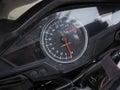 A round speedometer with a red arrow is located on a black motorcycle. Full screen photo