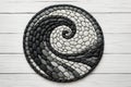 Round spiral stone mosaic in black and white design decorative handmade mandala element on wooden surface interior harmony concept Royalty Free Stock Photo