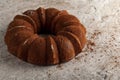 A round sponge cake fresh out of oven with crumbles and cacao powders cooling on top of a marble or stone