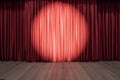 Round spotlight on red curtain on the stage with wooden floor