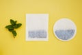 Round, square tea bags on yellow background and mint leaves, with copy space. Drinks and beverage. Royalty Free Stock Photo