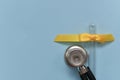 A round stethoscope membrane next to an empty inverted glass test tube with a yellow bow made of satin ribbon braid Royalty Free Stock Photo