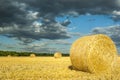 Round straw bales on mown grain field against dramatic sky with