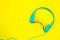 Round sunglasses and blue headphones on summer yellow background with copy space