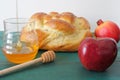 Round sweet challah, honey jar, red apple and pomegranate on a t