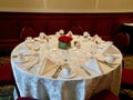 Round table set for wedding reception with white damask tablecloth, and red roses flower arrangement Royalty Free Stock Photo