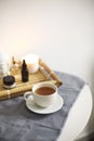 Round table in spa salon with cup of herbal tea next to bamboo tray with different aromatic oils