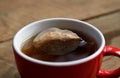 Round teabag floating at dark tea surface in red-white porcelain cup, detail of paper tea bag in hot water. Royalty Free Stock Photo