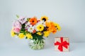 Round Vase with huge multicolor various mixed flower bouquet and shining golden gift box with red velvet ribbon