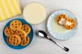 Round waffles with condensed milk in saucer, bowl with condensed milk, napkin, saucer with waffles, spoon on table. Top view Royalty Free Stock Photo