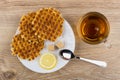 Round waffles, lemon, sugar, teaspoon in plate and tea