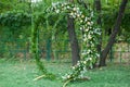 Round wedding arch decorated with various flowers on a green lawn