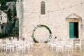 Round wedding arch stands in front of rows of white chairs near a church Royalty Free Stock Photo