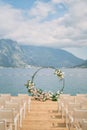 Round wedding arch stands on the pier in front of the chairs