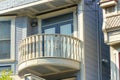 Round white balcony with wooden hand rails and banisters on house with blue paint and slatted tiles in suburban setting Royalty Free Stock Photo