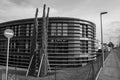 a round building sits along the side of a street with a sign posted next to Royalty Free Stock Photo