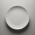 Round white ceramic plate is centered on a textured, light gray Royalty Free Stock Photo