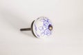 Round white drawer pull or knob with a blue flower design