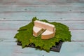 Round white homemade goat milk cheese on vine leaf on a wooden table Royalty Free Stock Photo