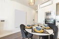 Round white marble dining table surrounded by upholstered chairs in a corner of an open-plan loft kitchen with a column of Royalty Free Stock Photo