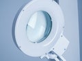 Round white medical operating lamp with reflection in glass in doctors office. Light blue interier background