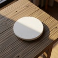 Round white object, possibly a ceramic coaster, positioned on a wooden table with Royalty Free Stock Photo