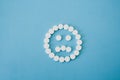 Round white pills sad smile on blue background Royalty Free Stock Photo