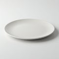 Round white plate with a smooth, matte finish placed on a plain white surface. The Royalty Free Stock Photo