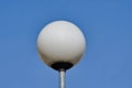 Round white streetlamp and blue sky background.