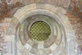 Round window with iron bars in an old brick temple. Arched decor of church in classic style Royalty Free Stock Photo