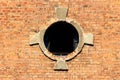 Round window opening with partially broken glass and decorative red bricks tiles frame on old abandoned industrial complex Royalty Free Stock Photo