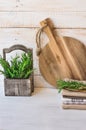 Round wood cutting board, stack of linen kitchen towels, fresh rosemary in vintage box on white plank wood background Royalty Free Stock Photo