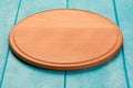 Round wooden cutting board for pizza on blue wooden table. Full depth of field. Mockup for food project