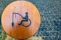 Round wooden handicapped fishing sign on shore of lake in public park Royalty Free Stock Photo